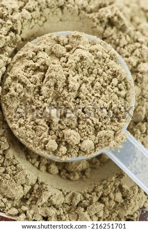 close up of plastic measuring scoop filled with raw organic hemp protein powder
