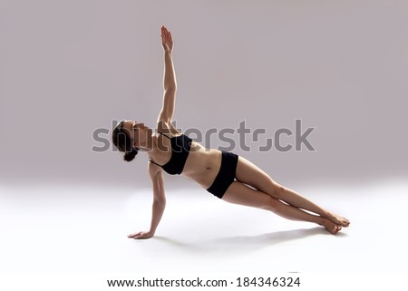 Caucasian woman is practicing yoga . In studio.  grey background.