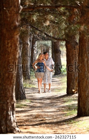Enamoured guy and the girl walk in wood. Young men, in the summer, in pine wood. A sunny day.
