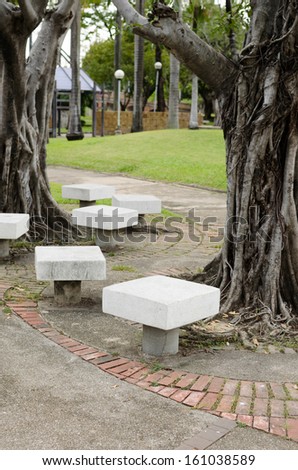 white stone chairs in the garden under the tree