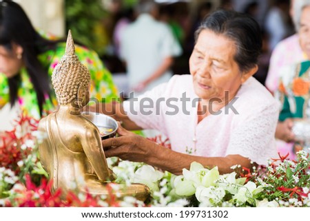 rayong thailand - april  20,2014 :people celebrate Songkran festival by pouring water on buddha statue and asking for blessings on april 20, 2014 in rayong,thailand .