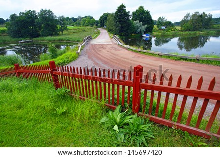 Landscape in Kastelholm area ( Aland Islands) with typical red road and red fence.