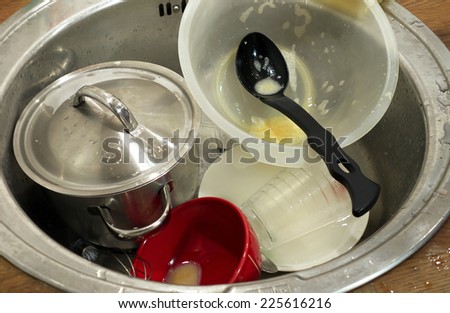 Unwashed dishes in kitchen sink waiting for automatic dishwasher.