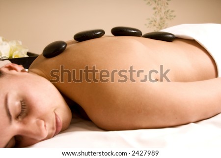 girl getting hot stone massage in day spa