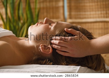woman in a day spa getting a head massage with green plant