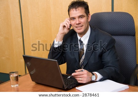 Businessman in a board room on the cell phone and laptop