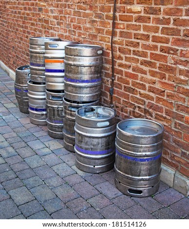 A line of aluminium barrels up against a brick wall