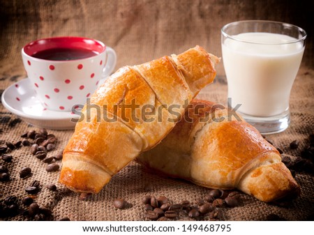 Fresh baked traditional French croissants with coffee and glass of yogurt in background