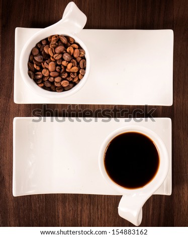 Raw coffee beans and prepared dark coffe in the cups from above