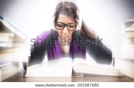 Tired female student looking at big book  with blurred background