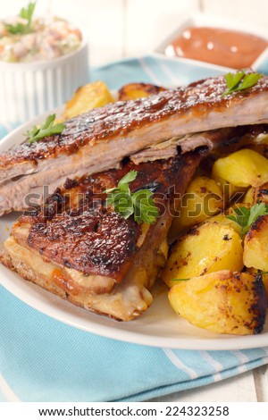 Plate with baked potato and beef ribs in bbq sauce,selective focus