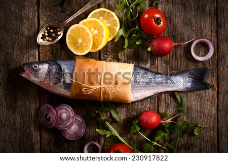 Raw bass fish with vegetables from above on the wooden background