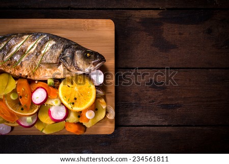Prepared bass fish on wooden background with blank space