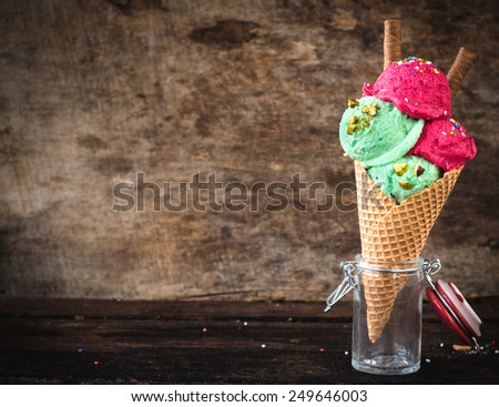 Fruit ice cream in cone on wooden background with blank space