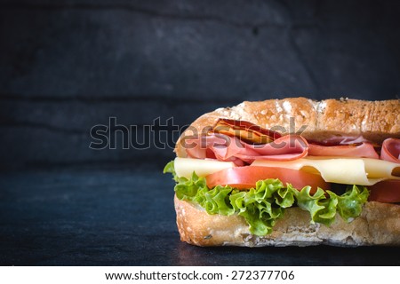 Ciabatta bread stuffed with cheese,meat and vegetables on dark background,selective focus and blank space