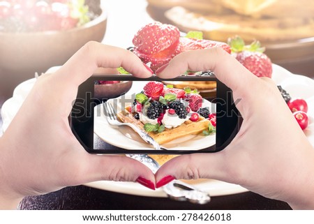 Female  photographing waffles with ice cream and berry fruits,selective focus