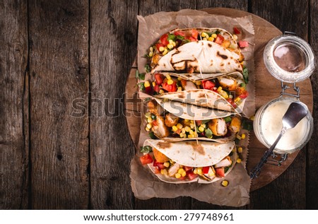Tortilla wrap sandwich with fried chicken and vegetables on wooden background,selective focus and blank space