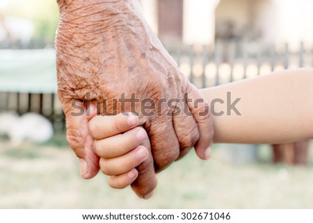 Grandchild holding grandparent for the hand,selective focus