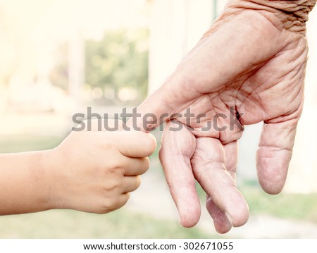Young child holding her grandparent for the hand,selective focus