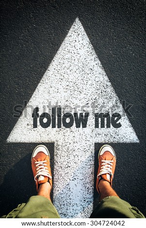 Red shoes standing on follow me sign