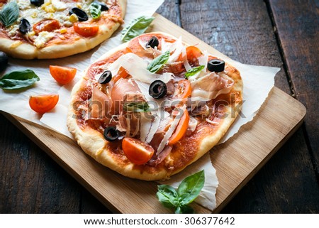 Served prosciutto mini pizza with parmesan cheese on wooden board,selective focus
