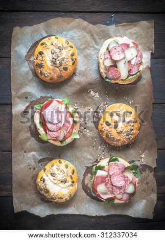Variety of sandwiches with sausages and homemade baked buns with seeds on top, high angle view