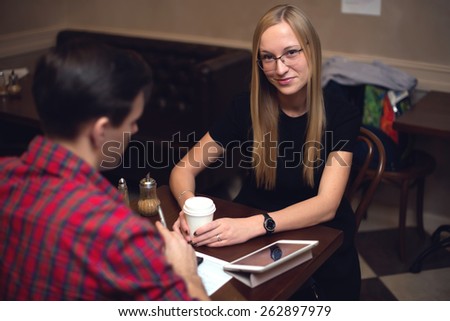 Young couple on a date in the cafe drinking coffee and chatting smiling.