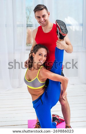 Young woman doing streching exercises with man smiling looking at camera concept training exercising workout fitness aerobic.
