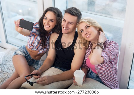 Happy friends two women and man taking selfie with camera or smartphone together wearing summer clothes  jeans shorts jeanswear street urban casual style having fun
