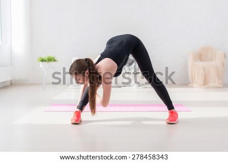 Athletic woman doing stretching exercise her hamstrings and back forward bend lean down aerobics or warming up with gymnastics at home.