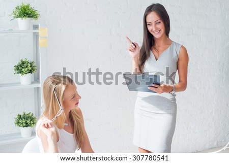 Two young woman colleague at office working and talking.