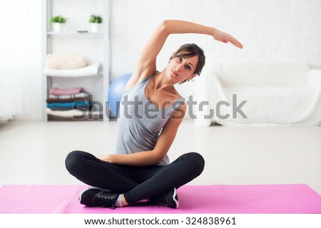 Fit woman stretching her back exercise for spine warm up concept aerobics gymnastics at home.