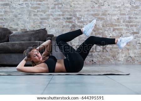 Sportive young lady doing crisscross crunch exercise lying on a rug at modern studio 商業照片 © 