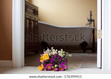 horizontal orientation close up of a bright bouquet in the foreground and deep, claw foot tub in an updated bathroom in the background with copy space / Updating your Bathroom