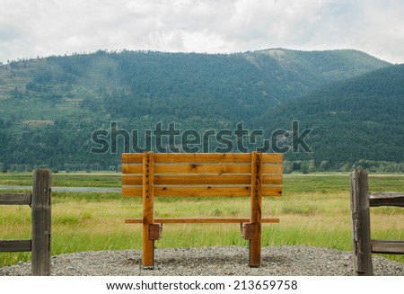 horizontal orientation of a single, empty, wooden bench in the foreground, with the majestic Selkirk Mountain Range in the background, and copy space / Spectacular Northern Idaho - Horizontal