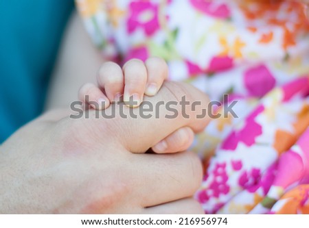 horizontal orientation close up of a baby girl\'s hand holding her father\'s hand with shallow depth of field / A Baby\'s Touch