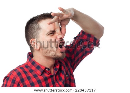 Young man with squares shirt over white background. Grabbing his nose with his fingers