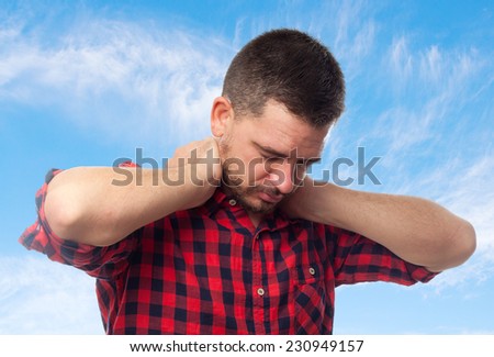 Young man with squares shirt over clouds background. Looking tired