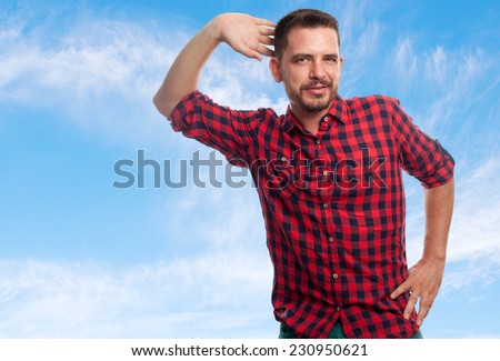 Young man with squares shirt over clouds background. Looking sexy