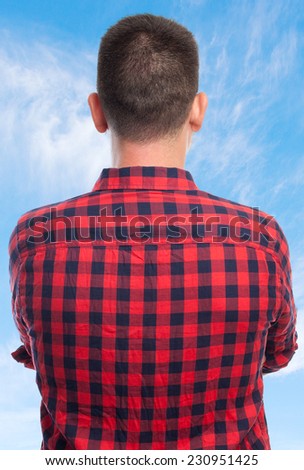 Young man with squares shirt over clouds background. He is giving his back