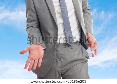 Man with grey suit over clouds background. Showing his empty pockets