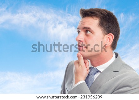 Young business man with grey suit over clouds background. Paying attention