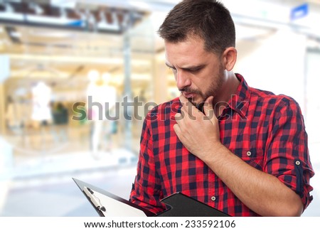 Man with red shirt over shopping center background. Paying attention to a black folder