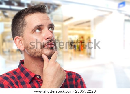 Man with red shirt over shopping center background. Looking surprised