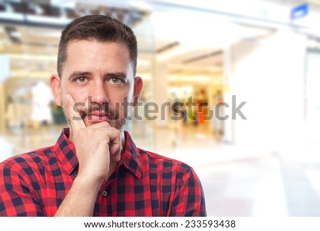 Man with red shirt over shopping center background. Looking confident