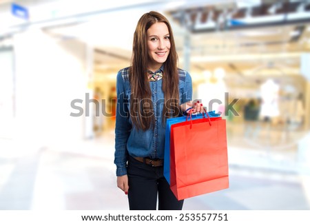 Trendy young woman with different colors shopping bags. Over shopping center background