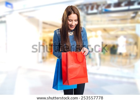 Trendy young woman with red and blue shopping bags. Over shopping center background