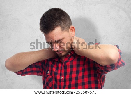 Man with red squares shirt. He looks tired. Over concrete wall