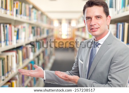 Business man with grey suit, he is offering something. Over library background
