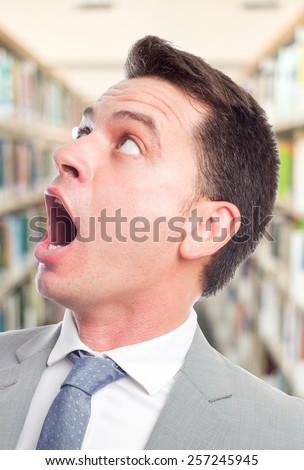Business man with grey suit. He is looking surprised. Over library background